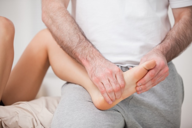 Reflexologist manipulating the foot of his patient while holding it on his thigh