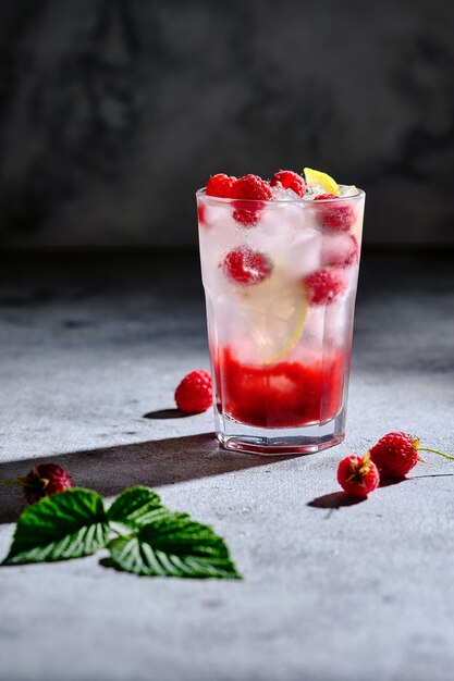 Refreshing alcoholic summer cocktail with raspberry liqueur and lemon. Ice drink garnished with mint and fresh berries.