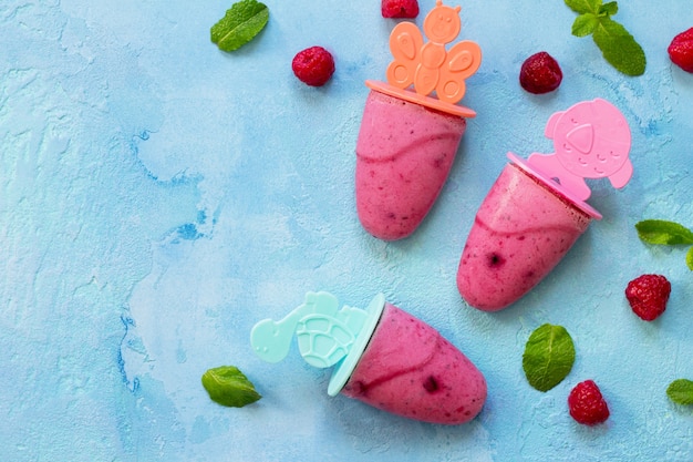 Refreshing childrens ice cream popsicles rasberry sorbet on blue concrete