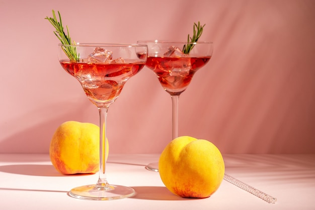Refreshing cocktail in a glass with a peach on a bright background