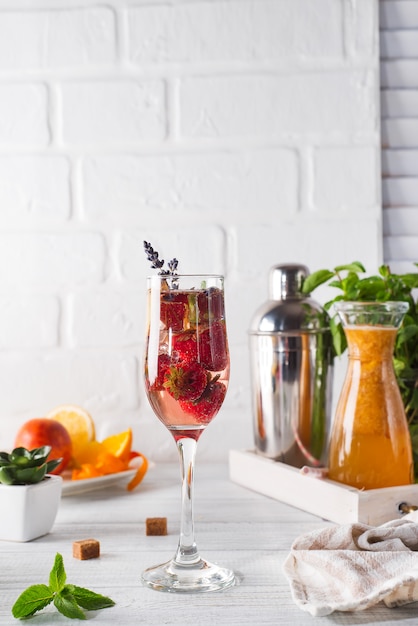 Refreshing cocktail with champagne and cranberry with ice, ginger and lavender on wooden