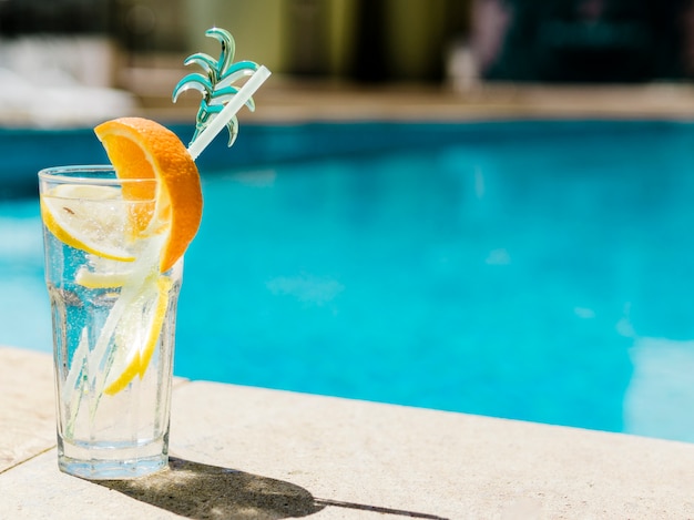 Photo refreshing cocktail with orange and lemon near pool