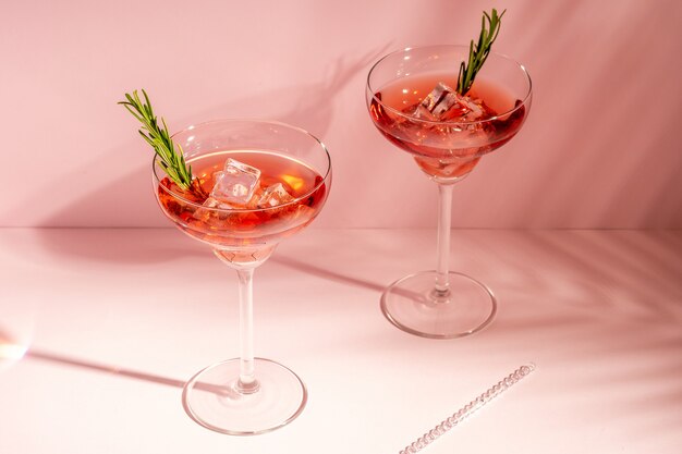 Cocktail rinfrescante con rosmarino in un bicchiere su uno sfondo luminoso.