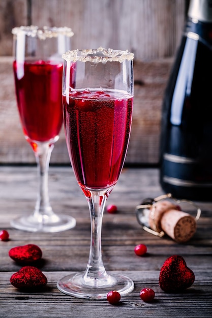 Refreshing cocktail with sparkling wine and cranberry for Valentine's day on wooden background