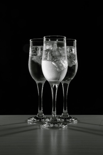 A refreshing, cold drink in glasses with ice on a black background.