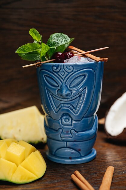 Refreshing cold Tiki Drink Cocktail with pineapple mango mint and cinnamon