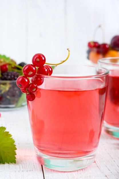 Refreshing drink compote of summer berries in glasses on a white wooden background