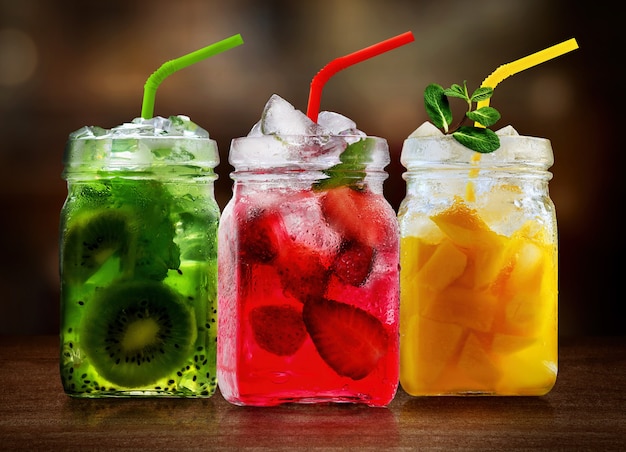 Photo refreshing fruits cocktails in glass jars on wooden table