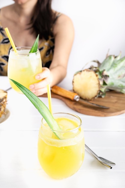 Refreshing homemade pineapple juice with ice Girl at a table drinking a pineapple juice