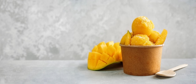 Фото Освежающий манго мороженое в бумажный стаканчик на сером фоне