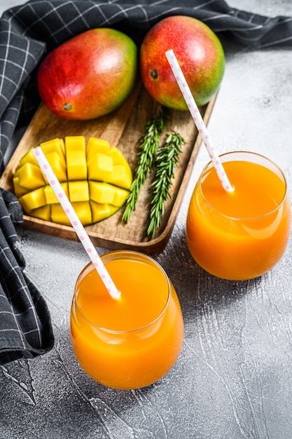 Refreshing mango juice in a glass. Gray background.