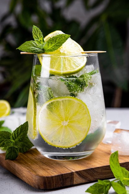 Refreshing mojito with lime mint and ice in a glass on a summer green