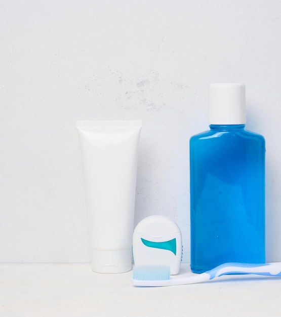 Refreshing mouthwash in a transparent plastic bottle and dental floss on a white background