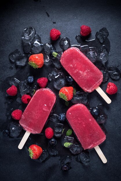 Photo refreshing popsicle on ice cubes and fruits