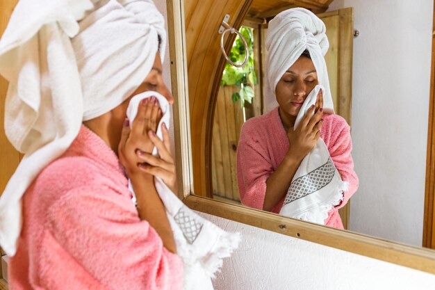 Rinfrescante donna latina selfcare che si asciuga il viso dopo la doccia