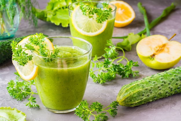 Refreshing smoothies from cucumber, green apple, fresh herbs and lemon juice in transparent glasses on the table. The concept of a healthy diet. Vegetarian menu