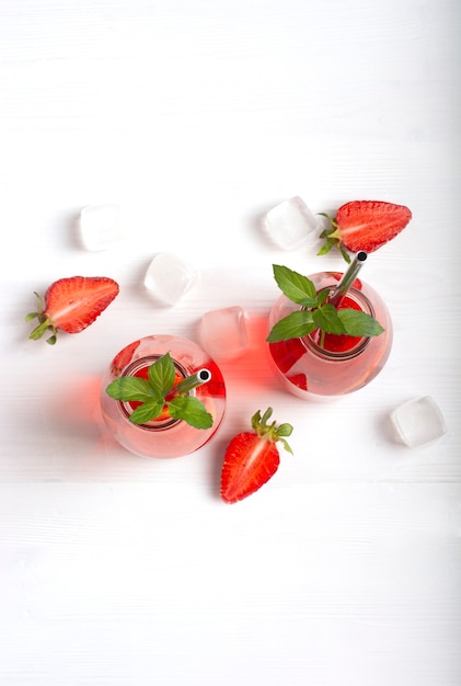 A refreshing strawberry drink with strawberries, lemon, mint, soda and ice in glass bottles