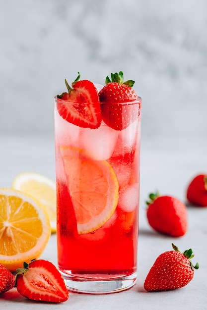 Refreshing Strawberry and lemon Iced Tea or lemonade in glass on a gray stone background