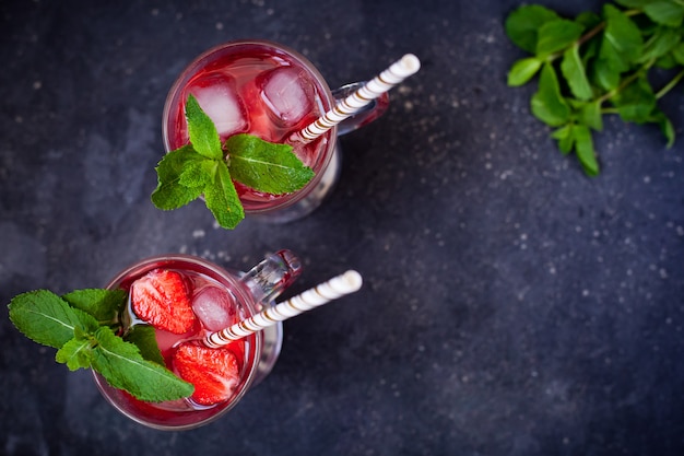 Bevanda estiva rinfrescante con menta, fragole e ghiaccio in bicchieri con cannucce