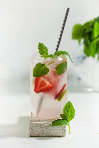 A refreshing summer drink with strawberries lemon and mint in a glass on a light background strawberry lemonade