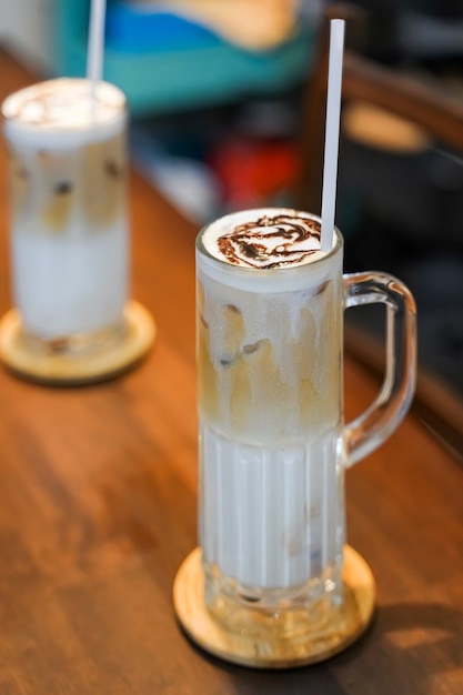 Refreshing summer drinks consists of three layers, cold milk, coffee, and cold foam milk in a tall glass.