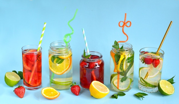 Refreshing summer drinks of lemon, lime, strawberry, orange, mint on a blue surface. Detox, healthy eating, fitness drinks. Travel concept.Copy space.