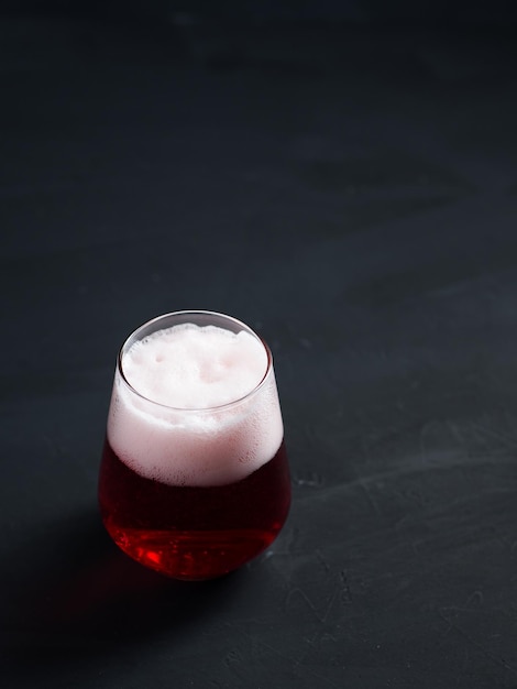 Refreshing summer fruit beer in a glass on a dark concrete table and copy space