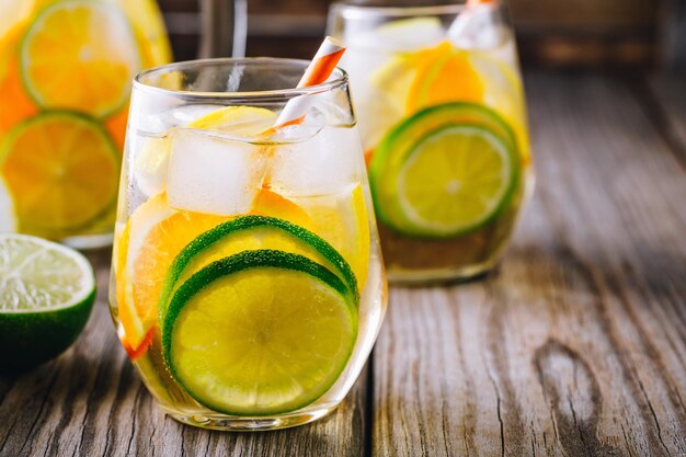 A refreshing summer icecold drink white wine sangria in glass with lime lemon and orange on a wooden rustic background