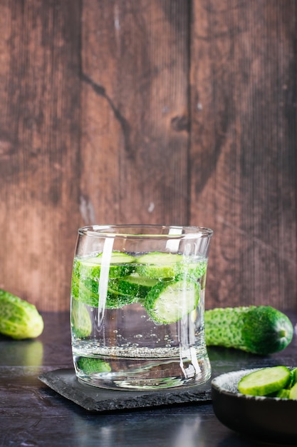 Refreshing water with cucumber in a glass on the table Homemade antioxidant drinks Vertical view