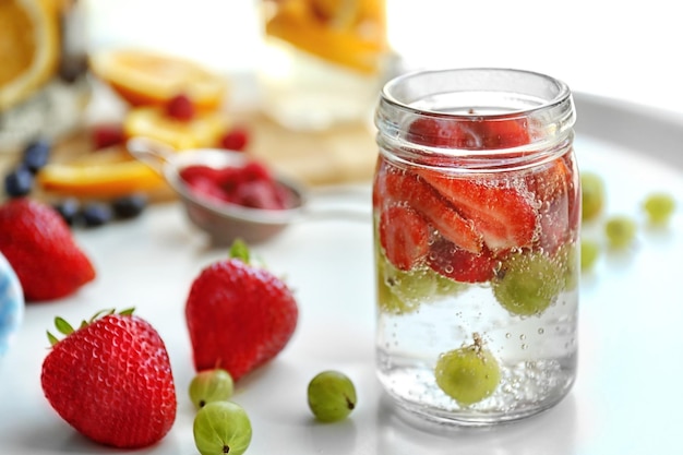 Refreshing water with fruits on table