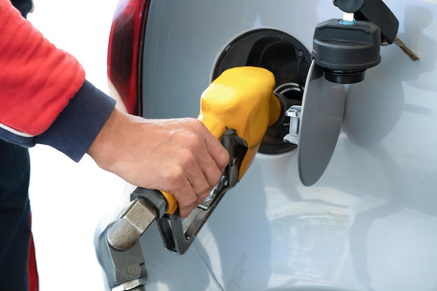 写真 ガソリンスタンドでガソリン燃料で車に燃料を補給している男性の手にガソリンを補給する銃