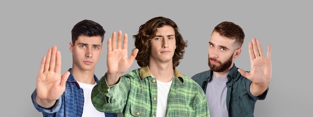 Photo refusal concept group of serious young men showing stop gesture at camera