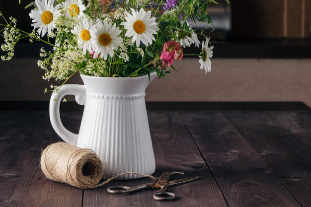 Regeling wilde bloemen in vaas op houten tafel