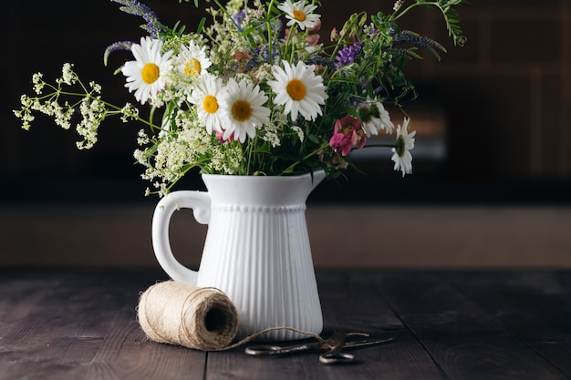 Regeling wilde bloemen in vaas op houten tafel