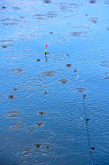 Regen op de rivier tijdens het vissen Vissen drijft op het water terwijl het regent Druppels water vallen op het oppervlak van de rivier tijdens regen Waterdruppels op het rivieroppervlak