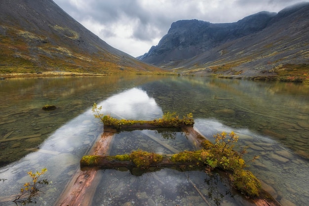 Regenachtige noordelijke bergen en meer met een verwoeste pier in de herfst