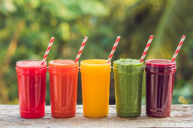 Regenboog van smoothies. watermeloen, papaya, mango, spinazie en drakenfruit. smoothies, sappen, dranken, drankenvariatie met vers fruit op een houten tafel