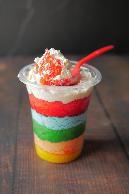 Regenboogkleurige cake in een plastic bak op tafel