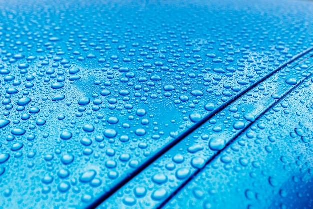 Regendruppels close-up op een turquoise carrosserie met hydrofoob effect