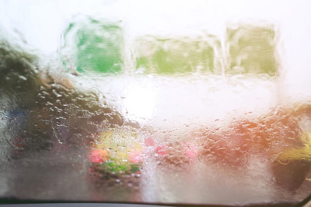 Regendruppels druppel op de glazen voorruit in de avondstraat in de zware regen Bokeh achterlicht en verkeerslichten in de stad Rij voorzichtig op de glibberige weg zachte focus