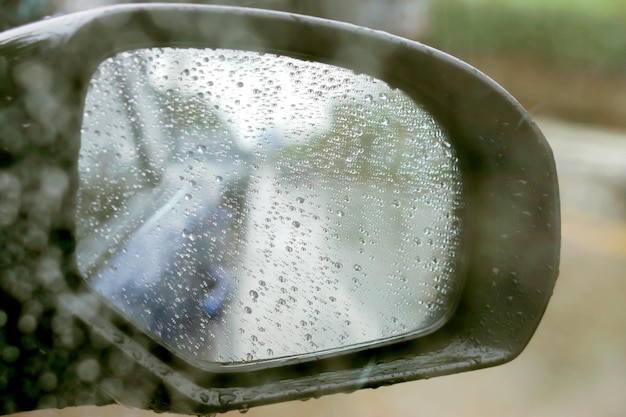 Regendruppels op autospiegel met zijspiegel op regenachtige dag