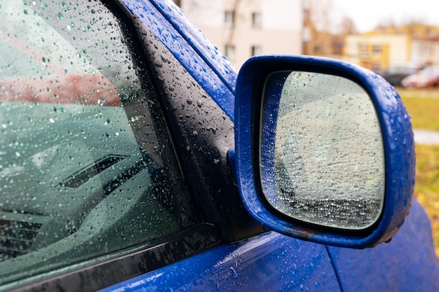 Regendruppels op de zijspiegel van een blauwe auto