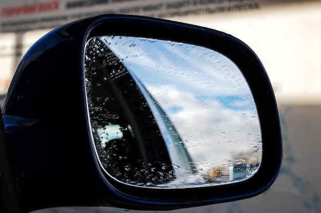 Regendruppels op de zijspiegel van een blauwe auto