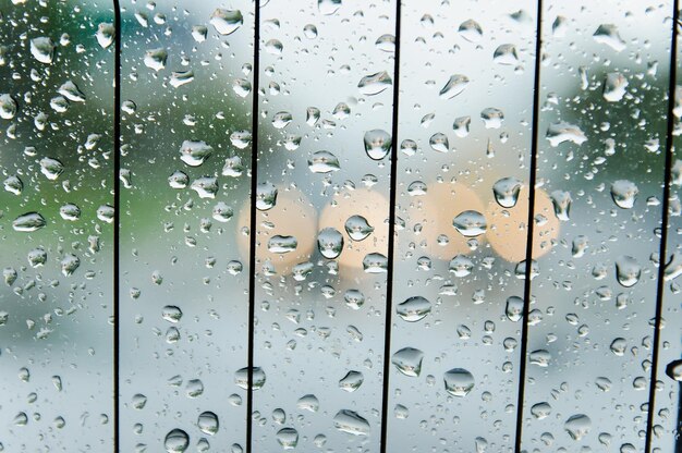 Regendruppels op het oppervlak van het autoglas bij regenachtig weer met een onscherpe achtergrond