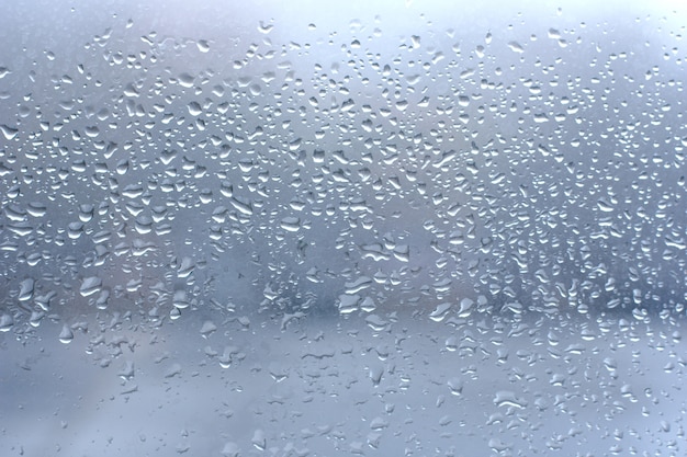 Regendruppels op schoon blauw vensterglas