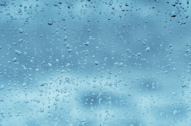 Regendruppels op vensterglas, afgezwakt blauw