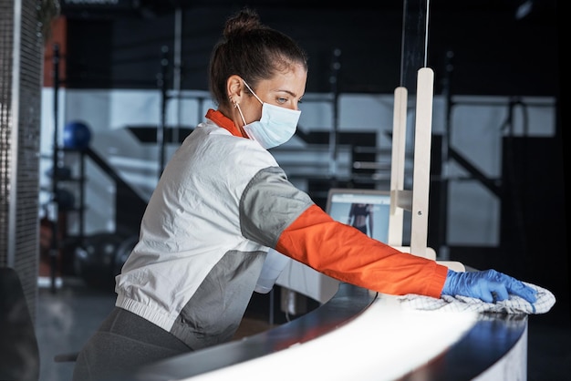 Regular cleaning is key to prevent the spread of germs Shot of a young woman cleaning the reception desk in a gym