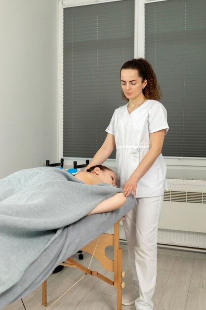 Rehabilitatie-specialist zet een draadloze elektrische spierstimulator op de rug van een gehandicapte