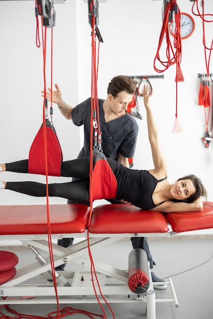 Rehabilitation specialist doing active treatment on suspension straps to a male patient