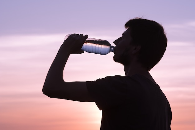 体に水分を補給します。水のボトルを飲む男性。